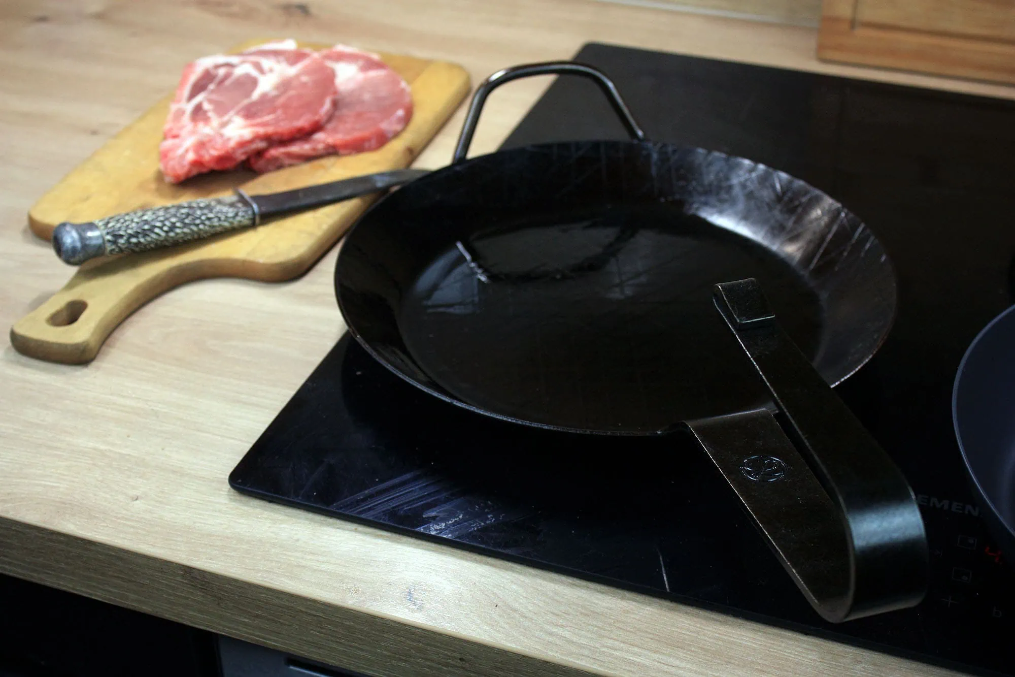 Die beste Eisenpfanne 188 Leutner PAN Ø 28 cm auf einem Induktionskochfeld mit gebogenem Stielgriff und Hilfsgriff.