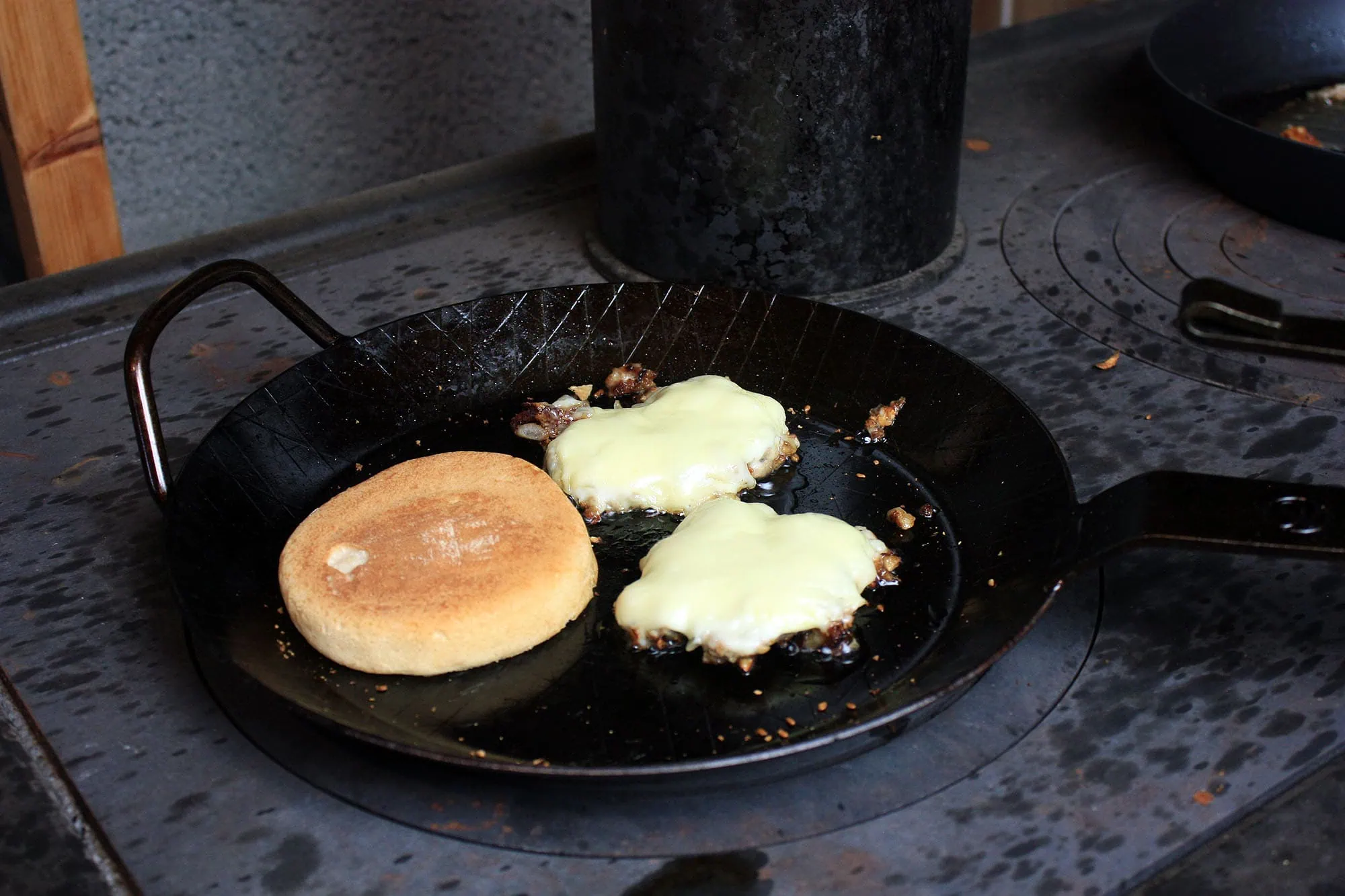 Die beste Eisenpfanne 193 Leutner PAN Ø 28 cm mit zwei Burger-Patties und einem Brötchen beim Braten.