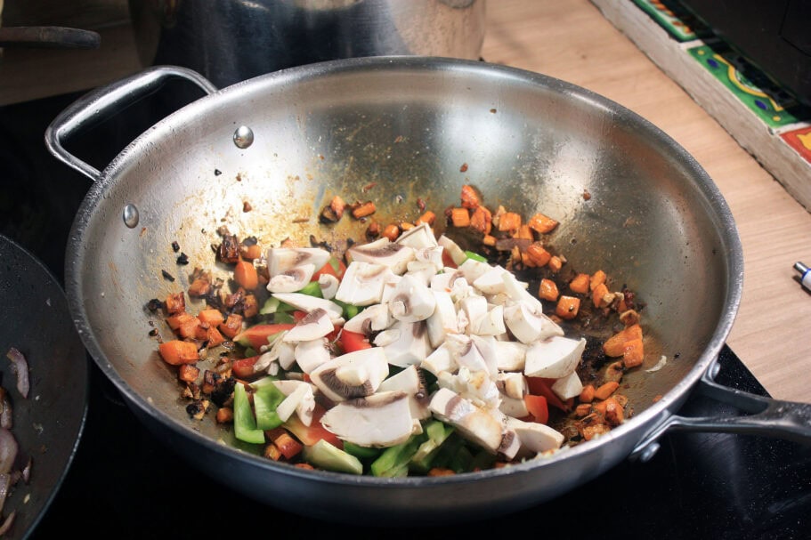 Die beste Wokpfanne 168 Geschnittene Pilze, Paprika und Karotten werden im Wok angebraten.